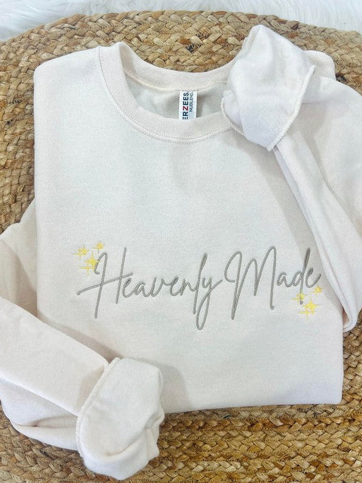 White sweatshirt with 'Heavenly Made' text on a woven surface