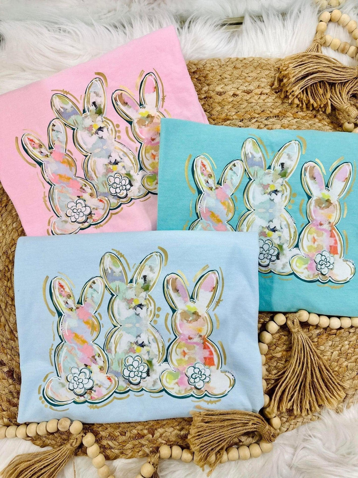 A collection of Easter-themed graphic tees with watercolor bunny designs, displayed on a neutral background.