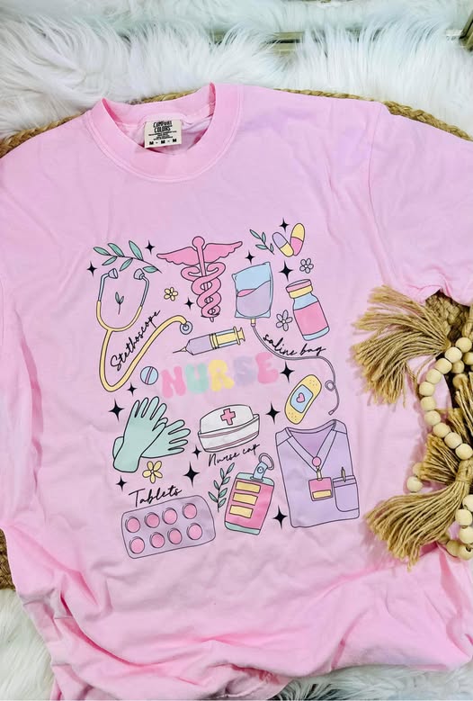 Pink t-shirt with medical-themed graphics on a fluffy white surface.