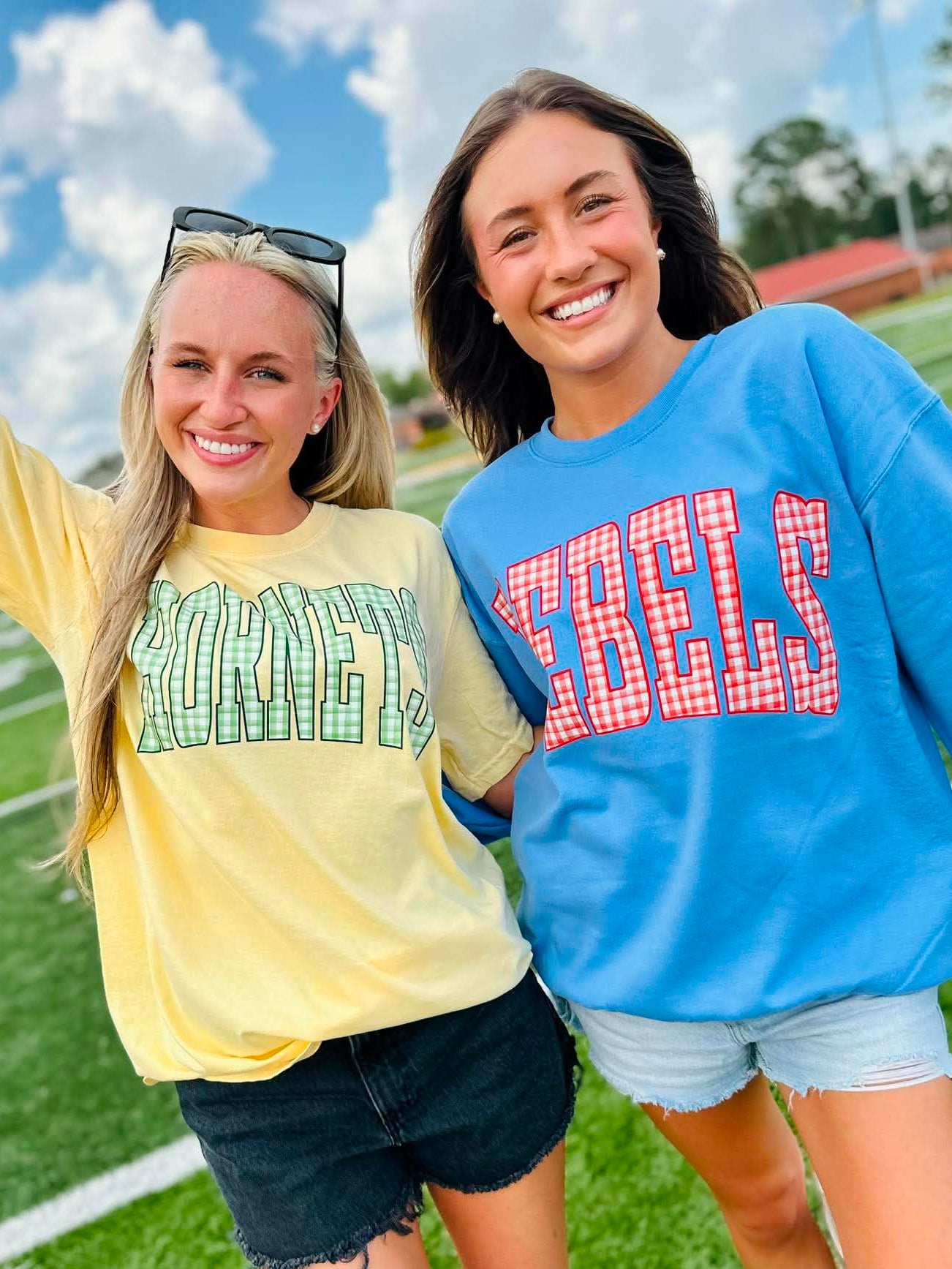 Two women standing on a football field wearing 'KENTUCKY' and 'REELS' shirts.